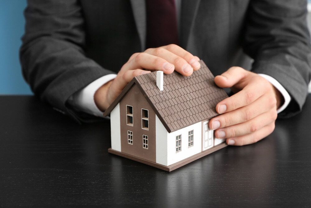A Man in a Suit and Tie is Holding a Model House in His Hands — Murphy Finance Solutions In Zuccoli, NT