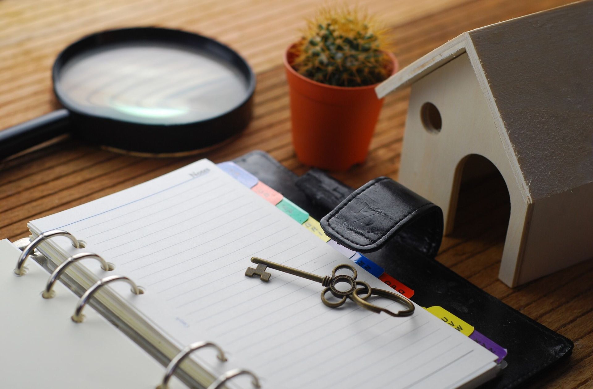 A Key is Sitting on Top of a Notebook Next to a Magnifying Glass and a Model House — Murphy Finance Solutions In Zuccoli, NT