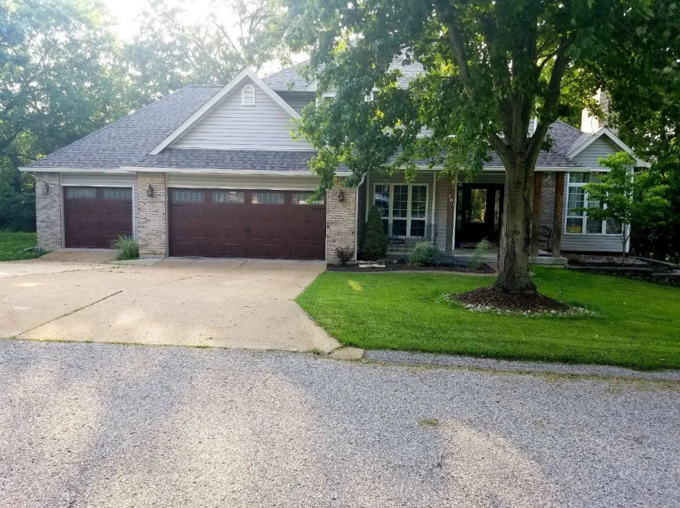Suburban house with three-car garage, front lawn, and large tree by the driveway