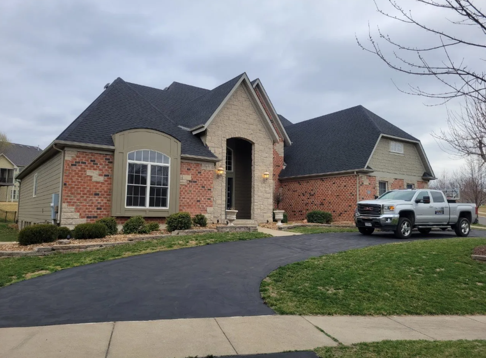 Suburban brick house with black roof and a pickup truck parked in the driveway.