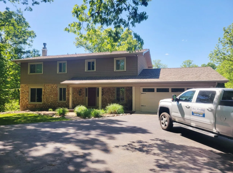 Two-story brick house with garage and white truck parked in driveway on a sunny day