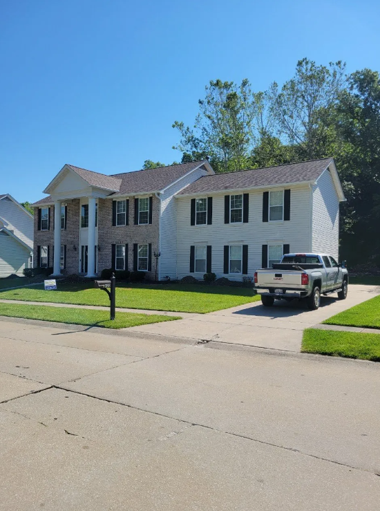 Suburban duplex with white siding and black shutters, parked pickup truck, and a residential street in front