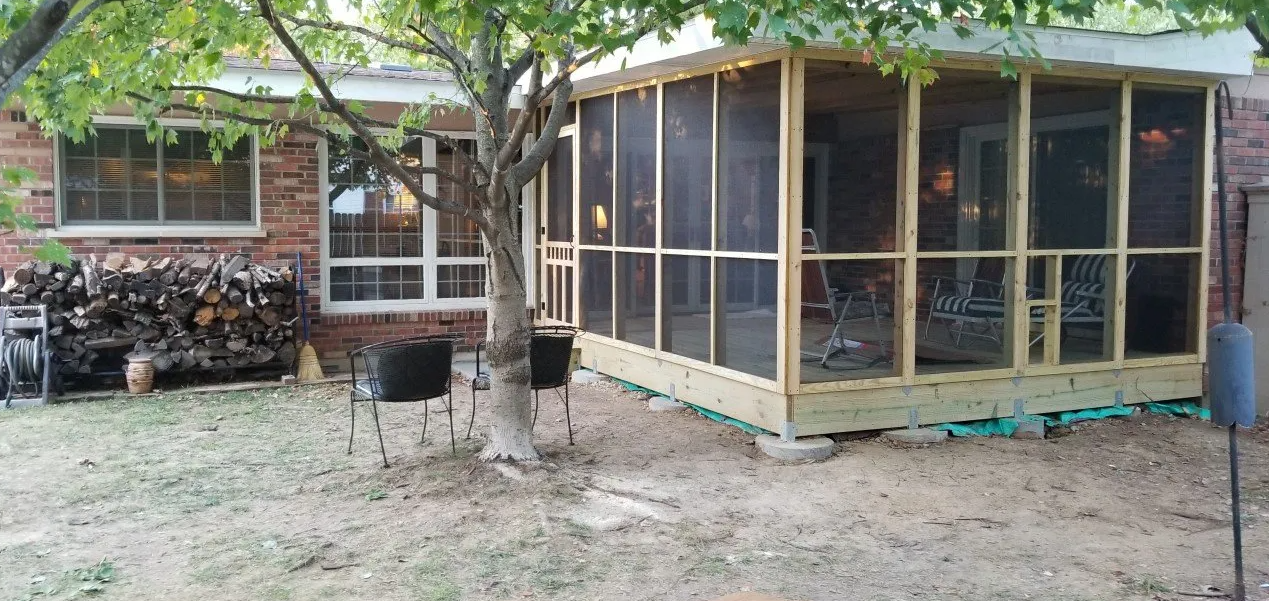 Backyard with a screened wooden shed beside a tree and parked motorcycles under leafy branches