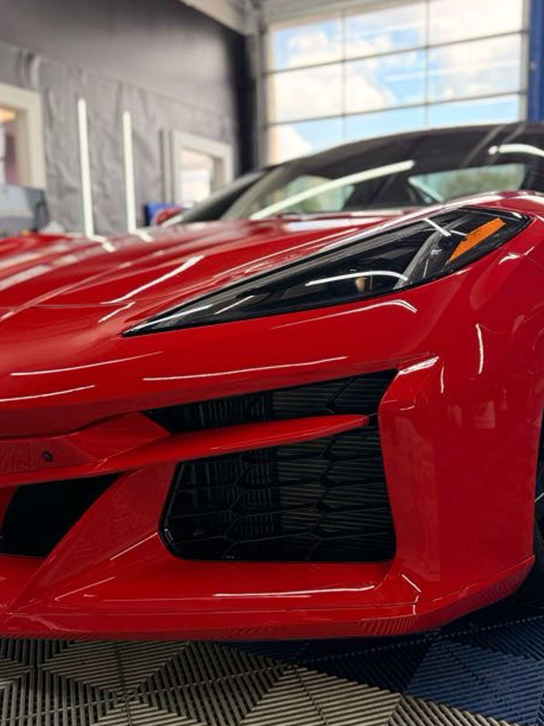 Gray sports car in a detailing shop with blue wall accents and neon lights
