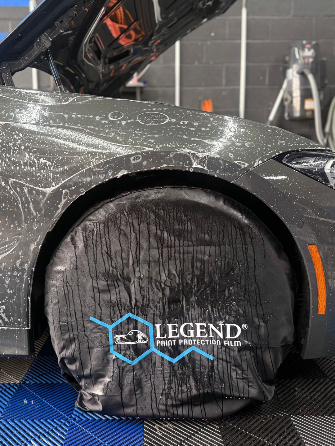 A person is washing a car wheel with foam