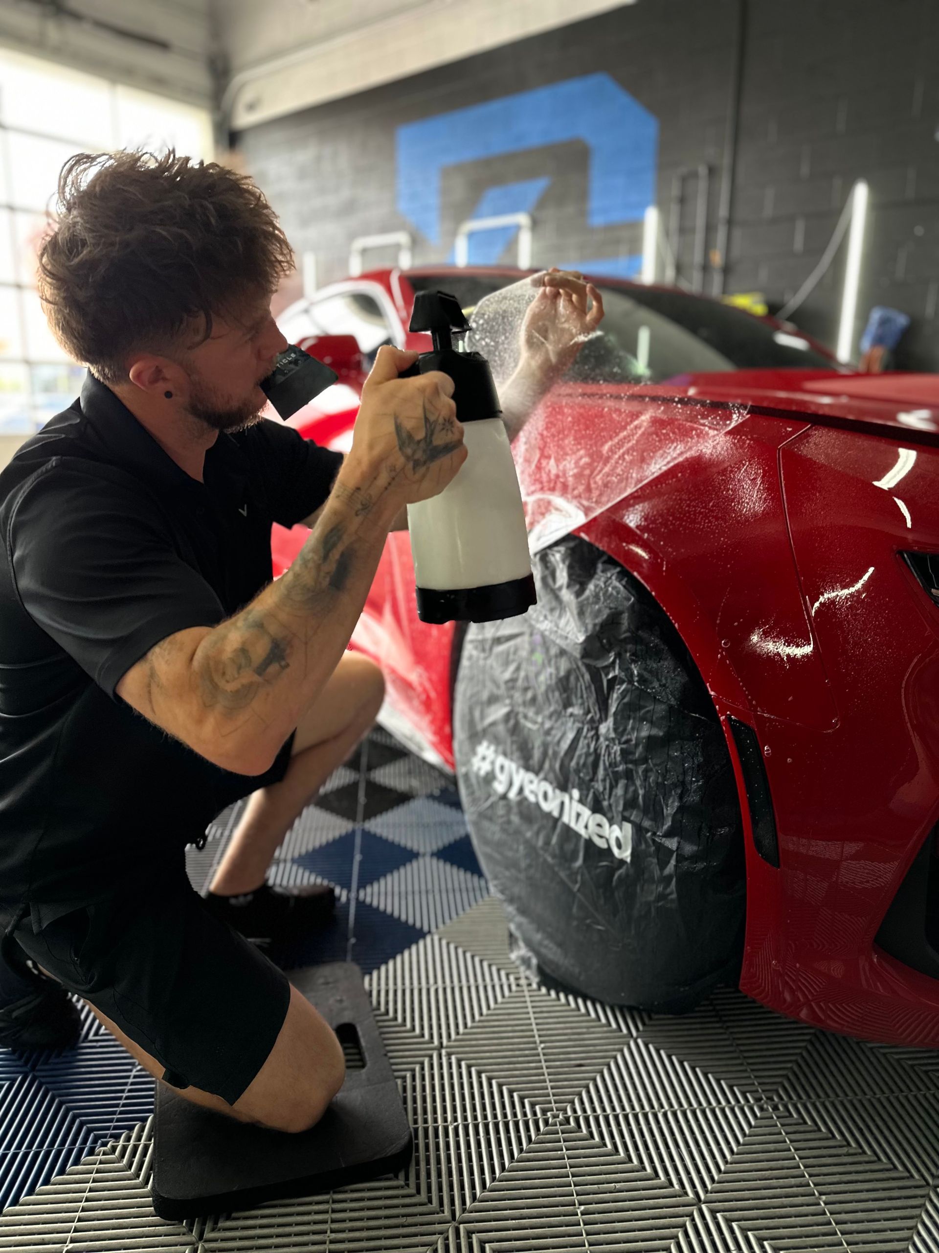 Person kneeling and applying decals to a red race car in a workshop