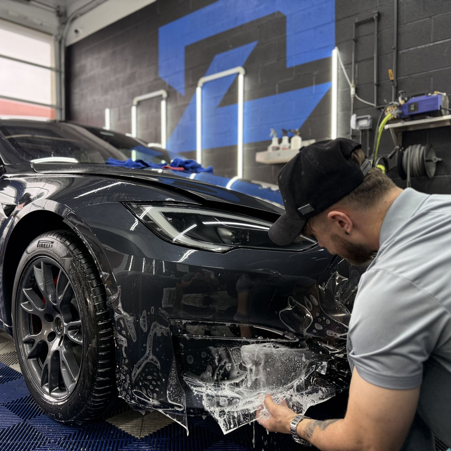 A person is cleaning a blue car with an orange towel