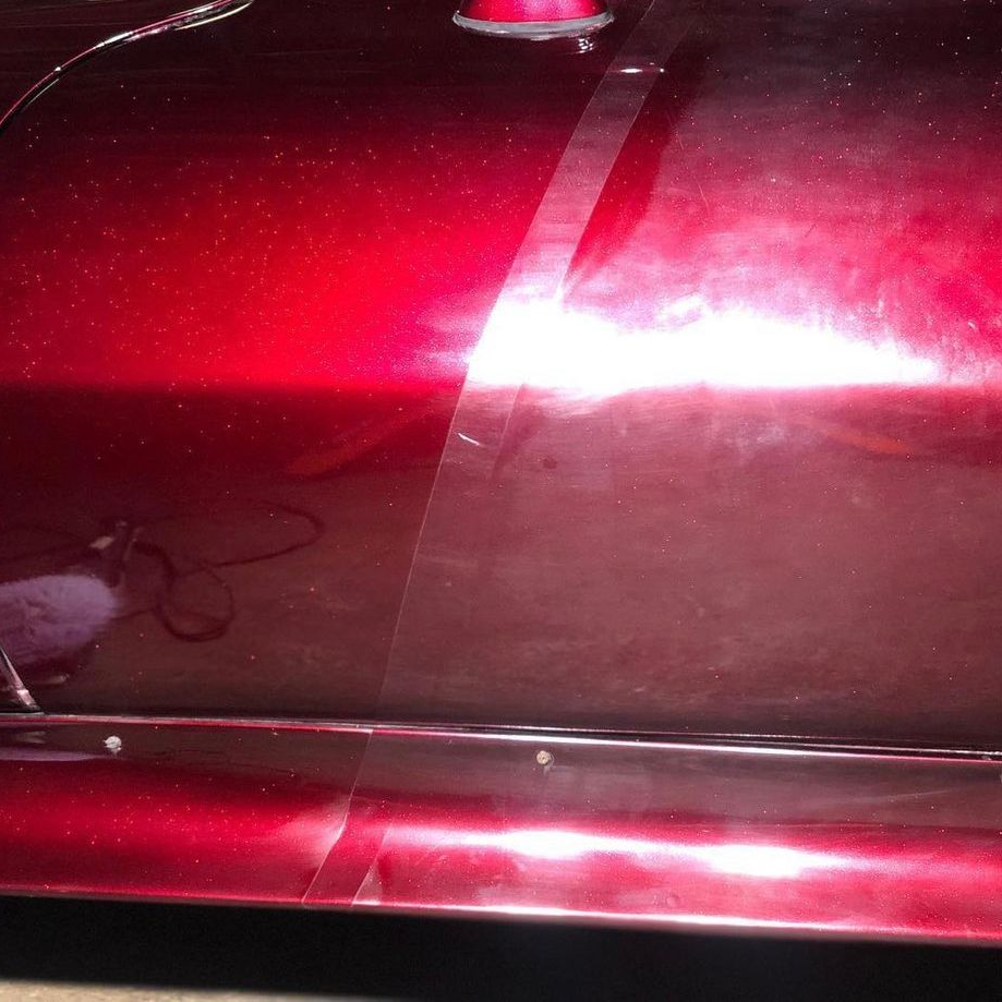 Red car door with bright red reflections and a chrome trim line