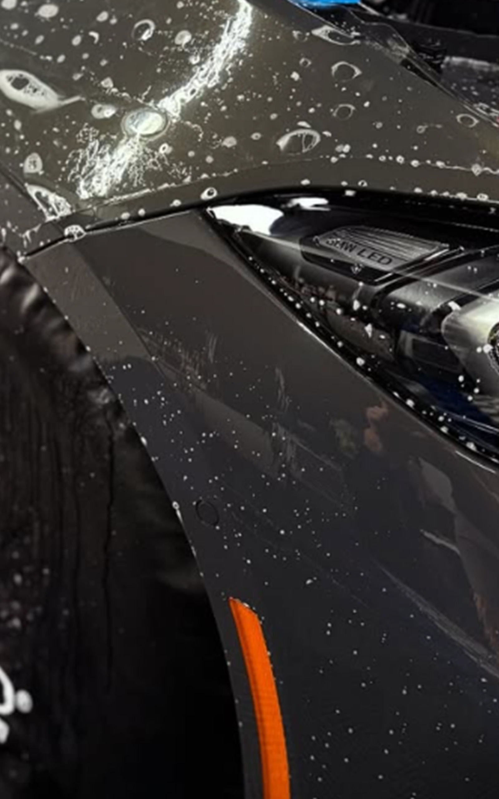 Hand peeling clear film from a wet car windshield during window tinting or cleaning