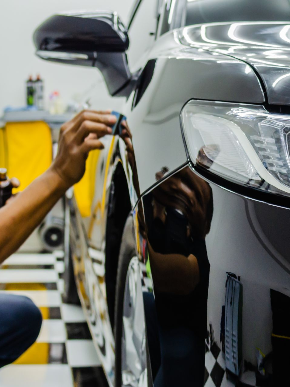 Mechanic polishing a black car in an auto shop with a cloth