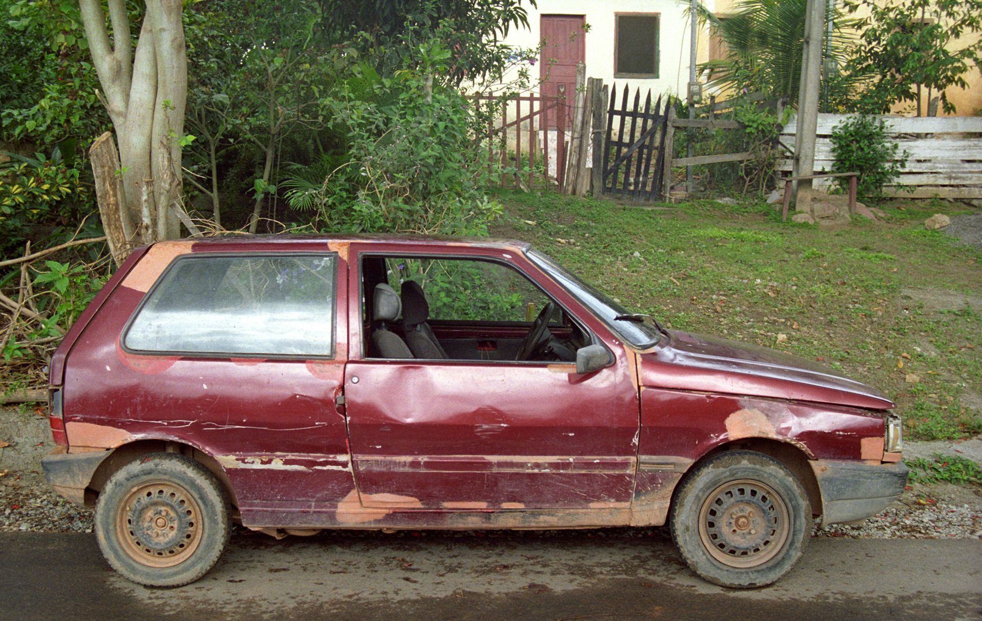 A red car is parked on the side of the road