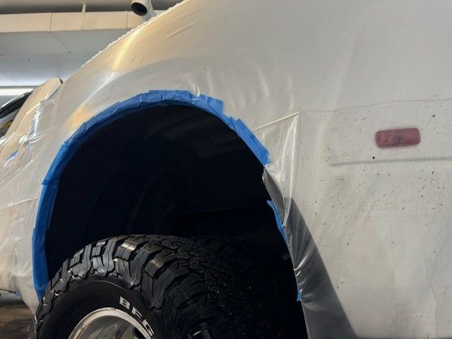 A close up of a red car with rust on the side.