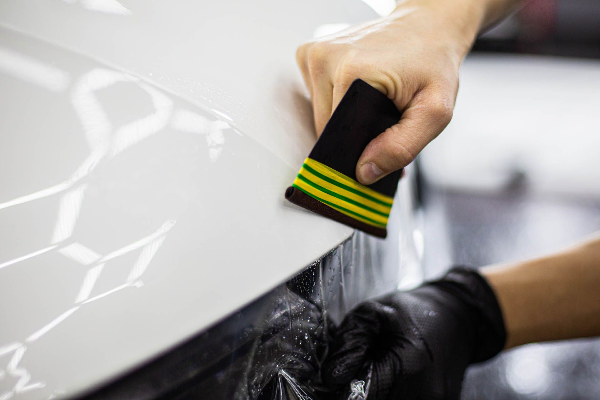 Hand washing a white car with a sponge and soapy water