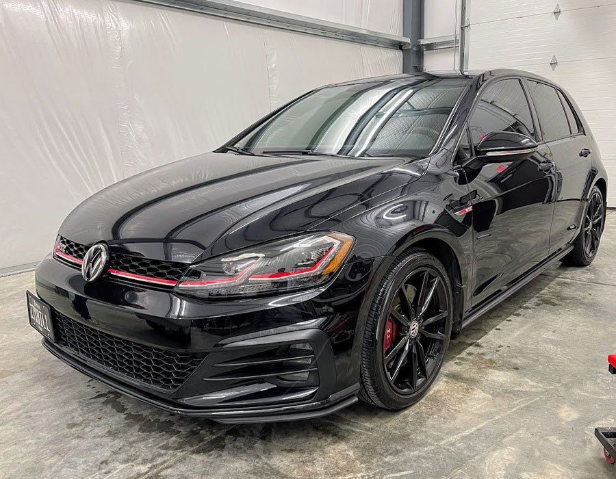A black volkswagen golf gti is parked in a garage.