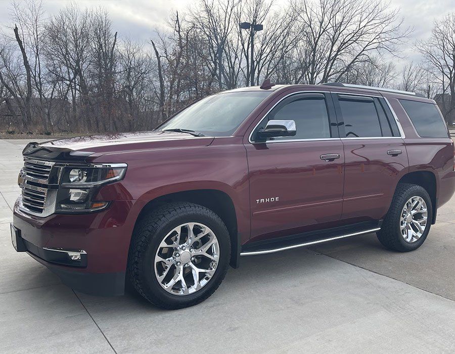 A red chevrolet tahoe is parked in a parking lot.