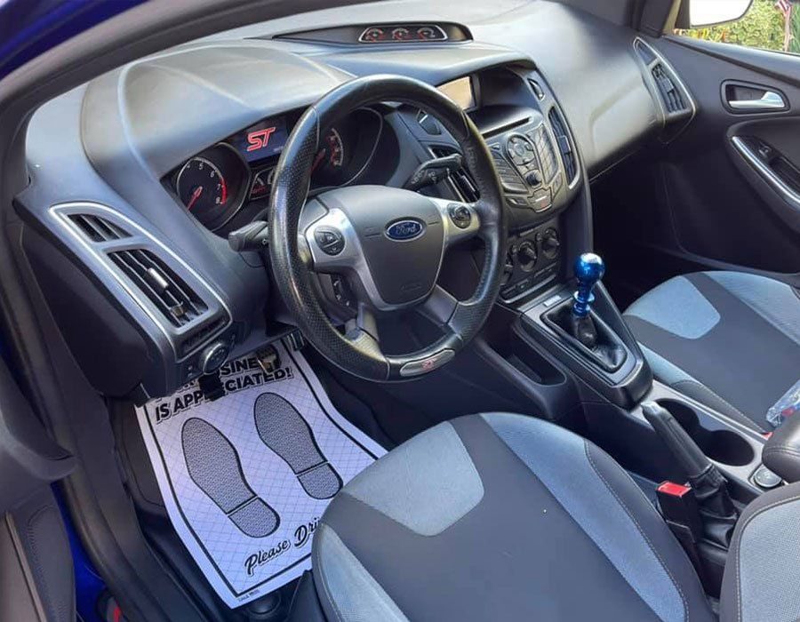 The interior of a blue ford focus with a steering wheel and seats