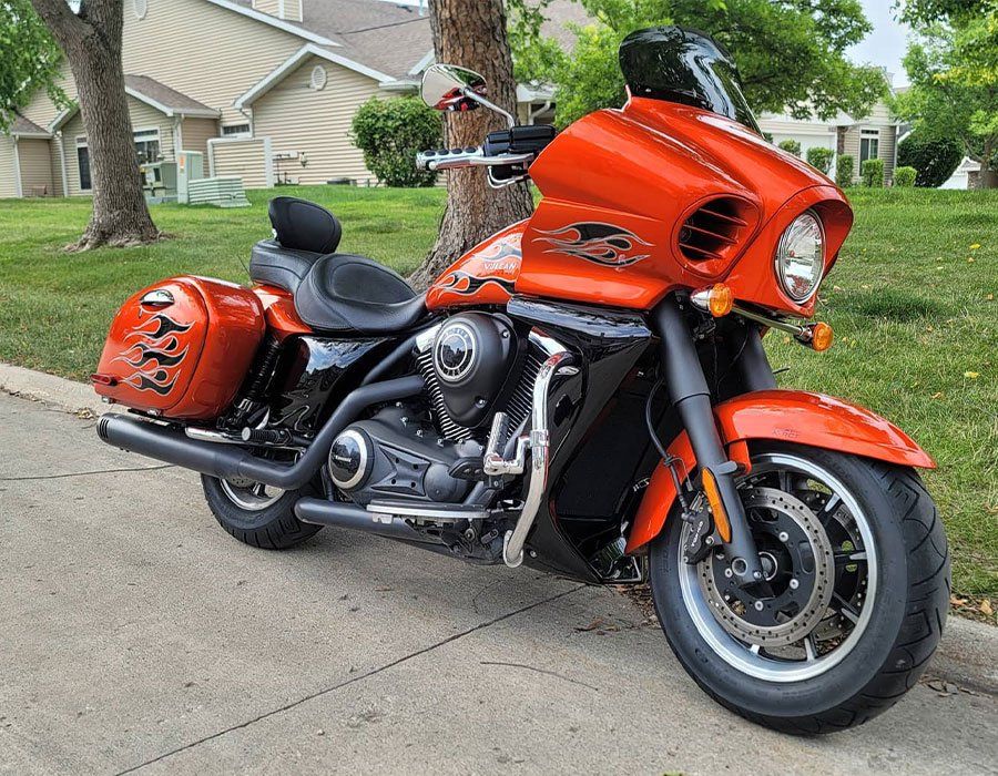 An orange motorcycle is parked on the side of the road.