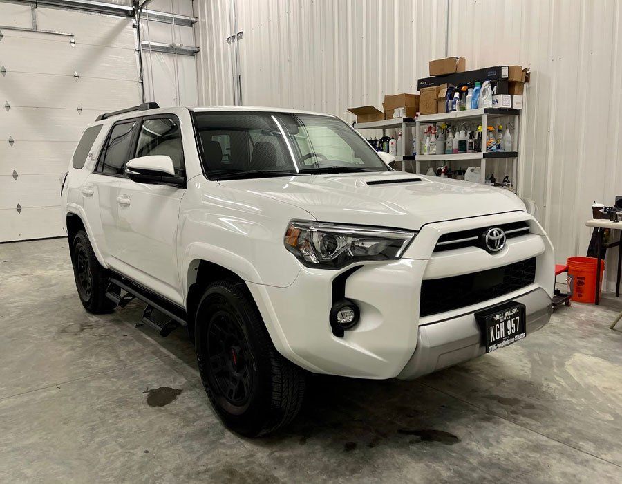 A white toyota 4runner is parked in a garage.