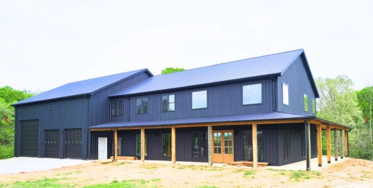 Modern dark-gray house with large windows and a covered porch in a wooded setting