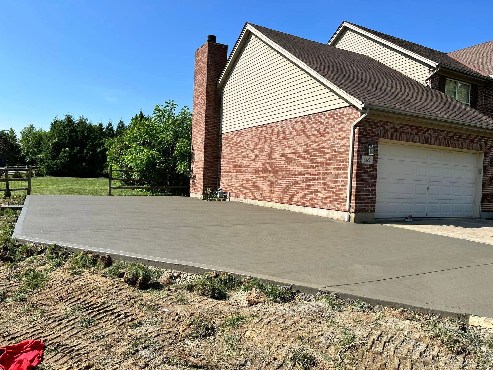 Brick house with white garage and long concrete driveway on a sunny day
