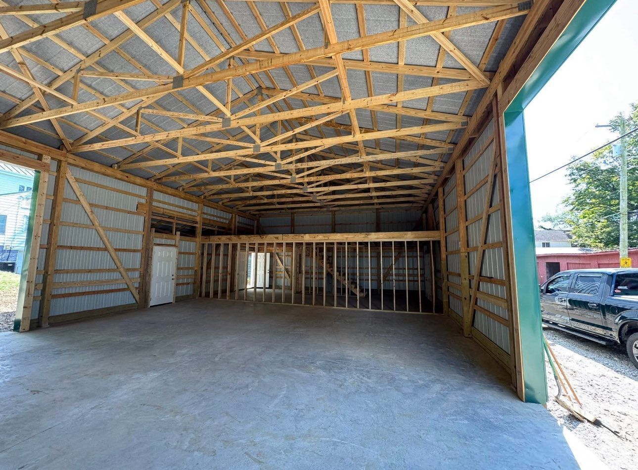 Interior of unfinished wooden garage with open front and exposed roof trusses