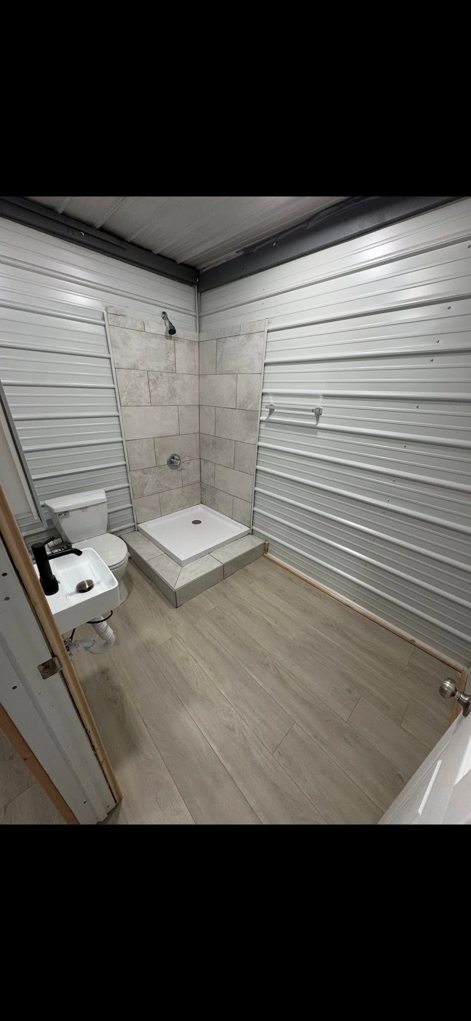 Small empty bathroom with white wall tiles, a toilet, and a low square shower basin.