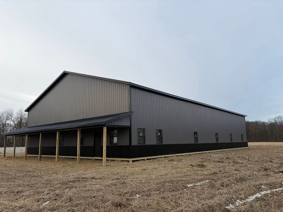 Large gray metal barn in a barren field under an overcast sky