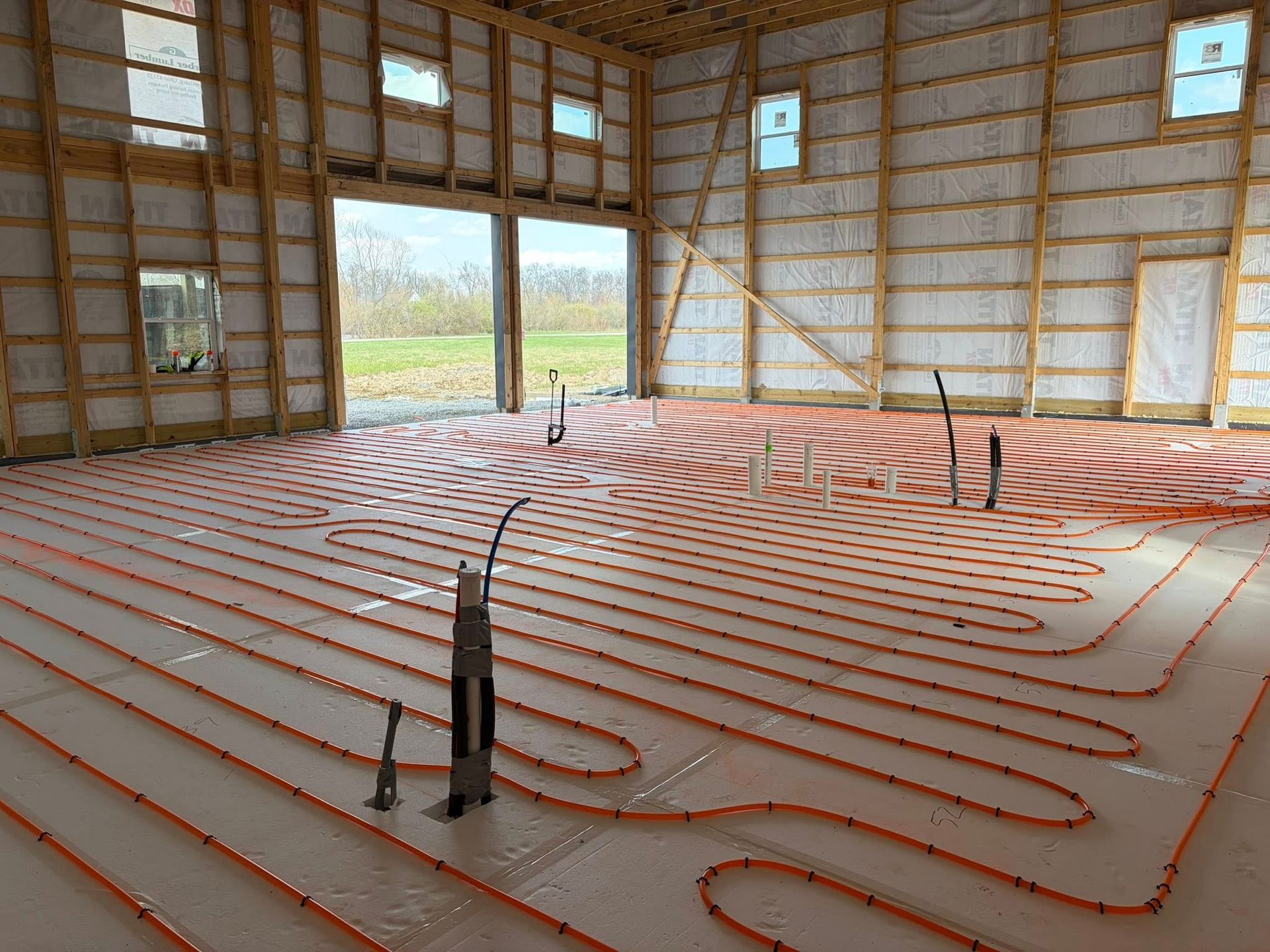 Interior of a house under construction with orange radiant floor heating tubes on the floor
