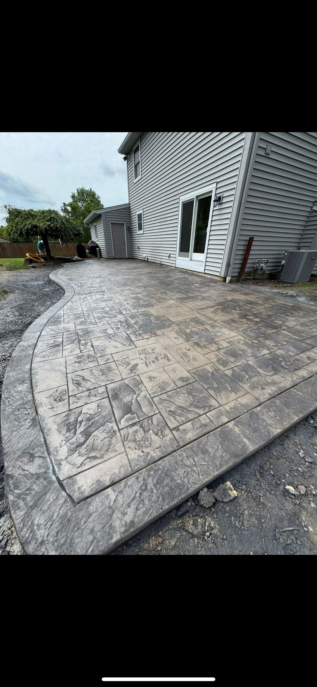 Damaged concrete driveway beside a gray house, with cracks and gravel around it