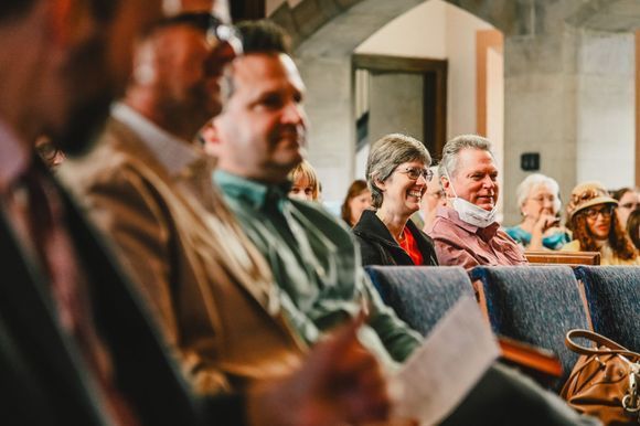 Audience seated in a church, smiling and listening during a gathering