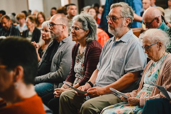 Audience seated in a lecture hall, listening attentively