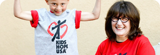 Smiling child in white T-shirt with arms raised beside smiling woman in red shirt