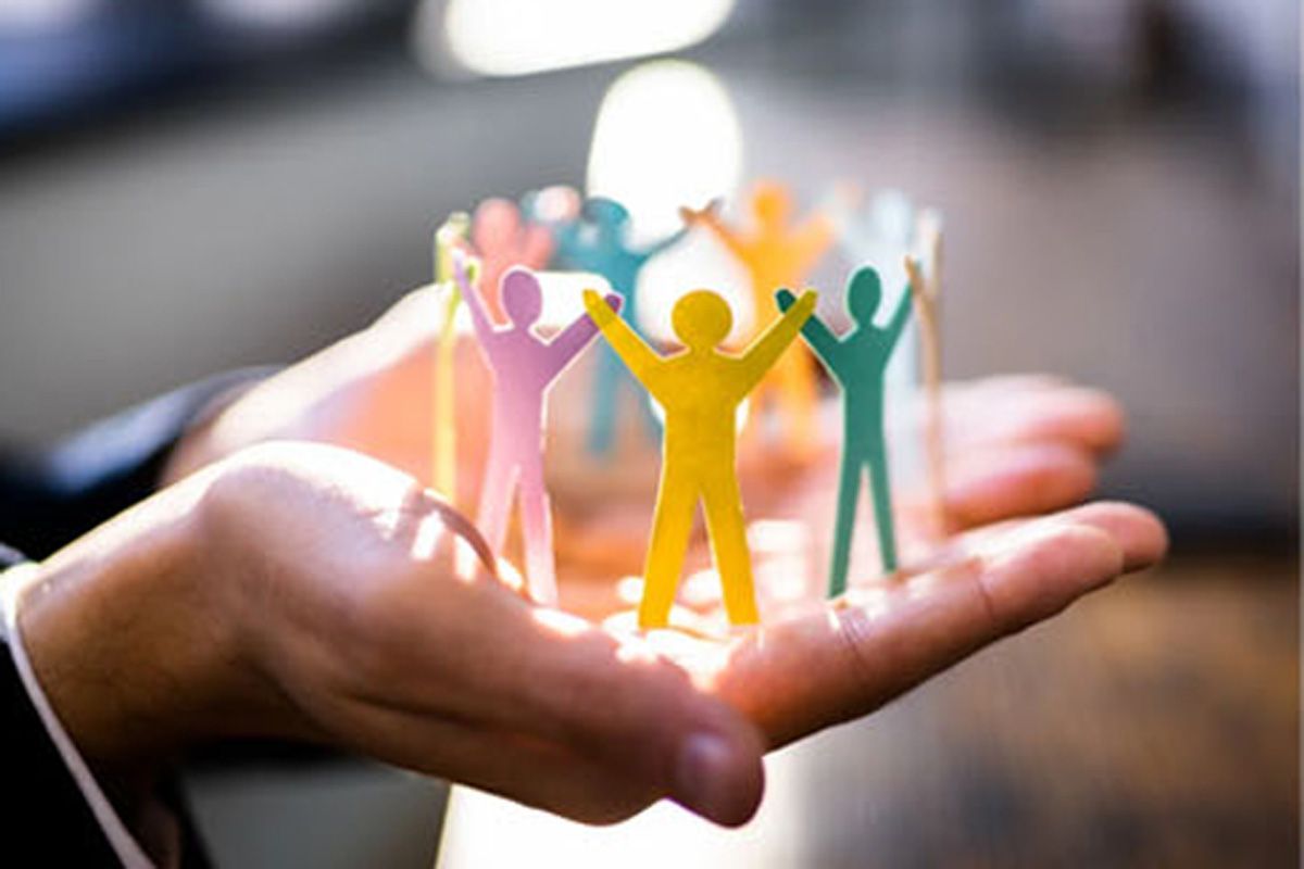 Hands holding colorful paper figures linked together in a glowing circle