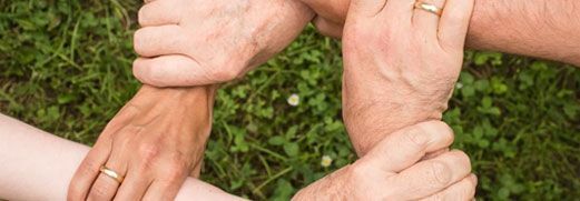 Linked hands forming a circle on green grass