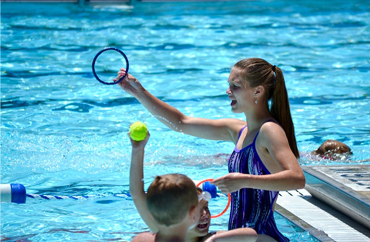 Children playing with rings and a tennis ball in a swimming pool