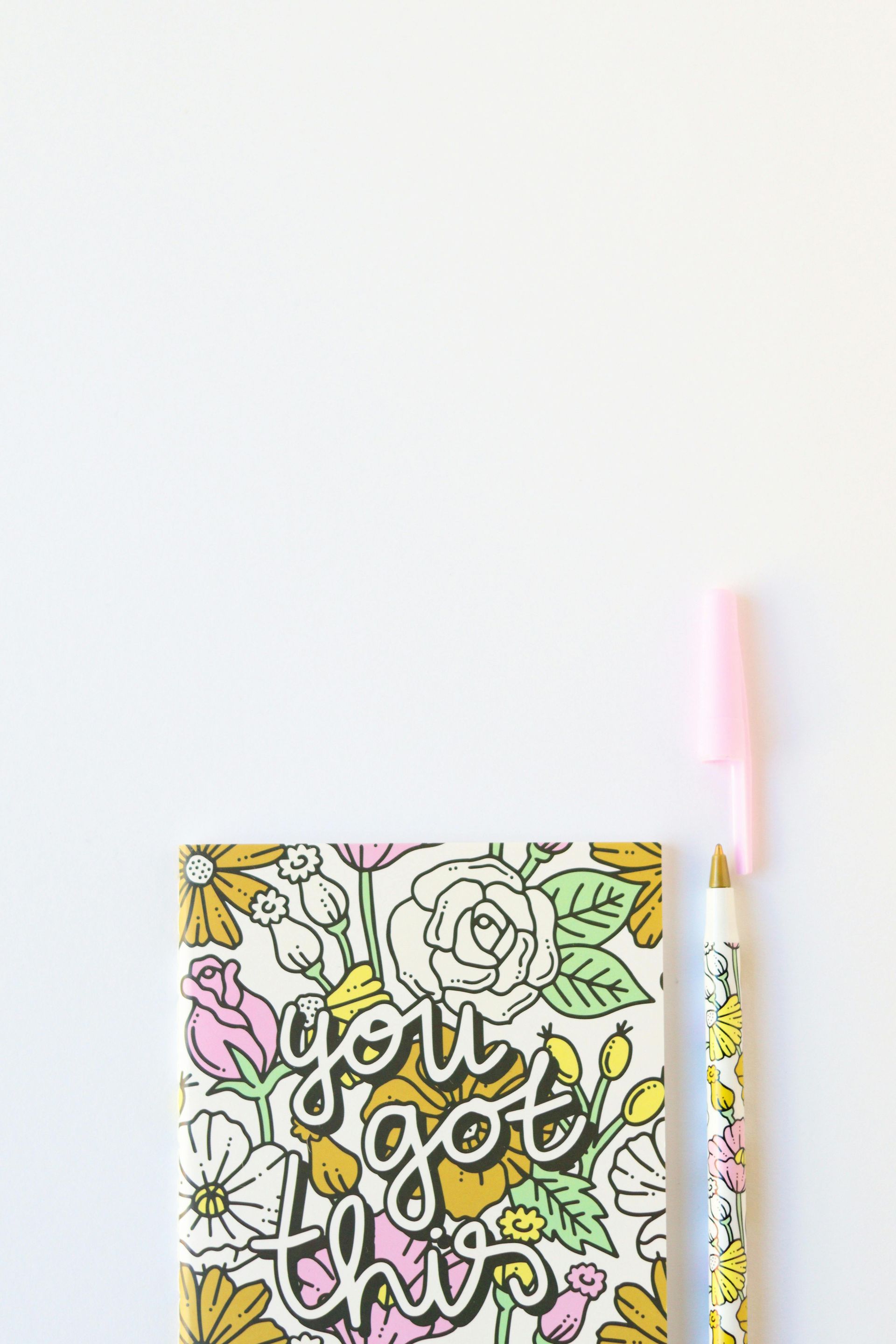 Een notitieboekje met een kleurrijke bloemenkaft waarop 