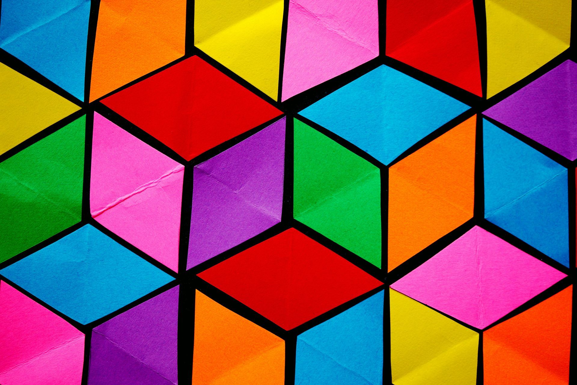 Een geometrisch patroon van kleurrijke papieren ruitjes, gerangschikt om een ​​3D isometrisch kubuseffect te creëren.