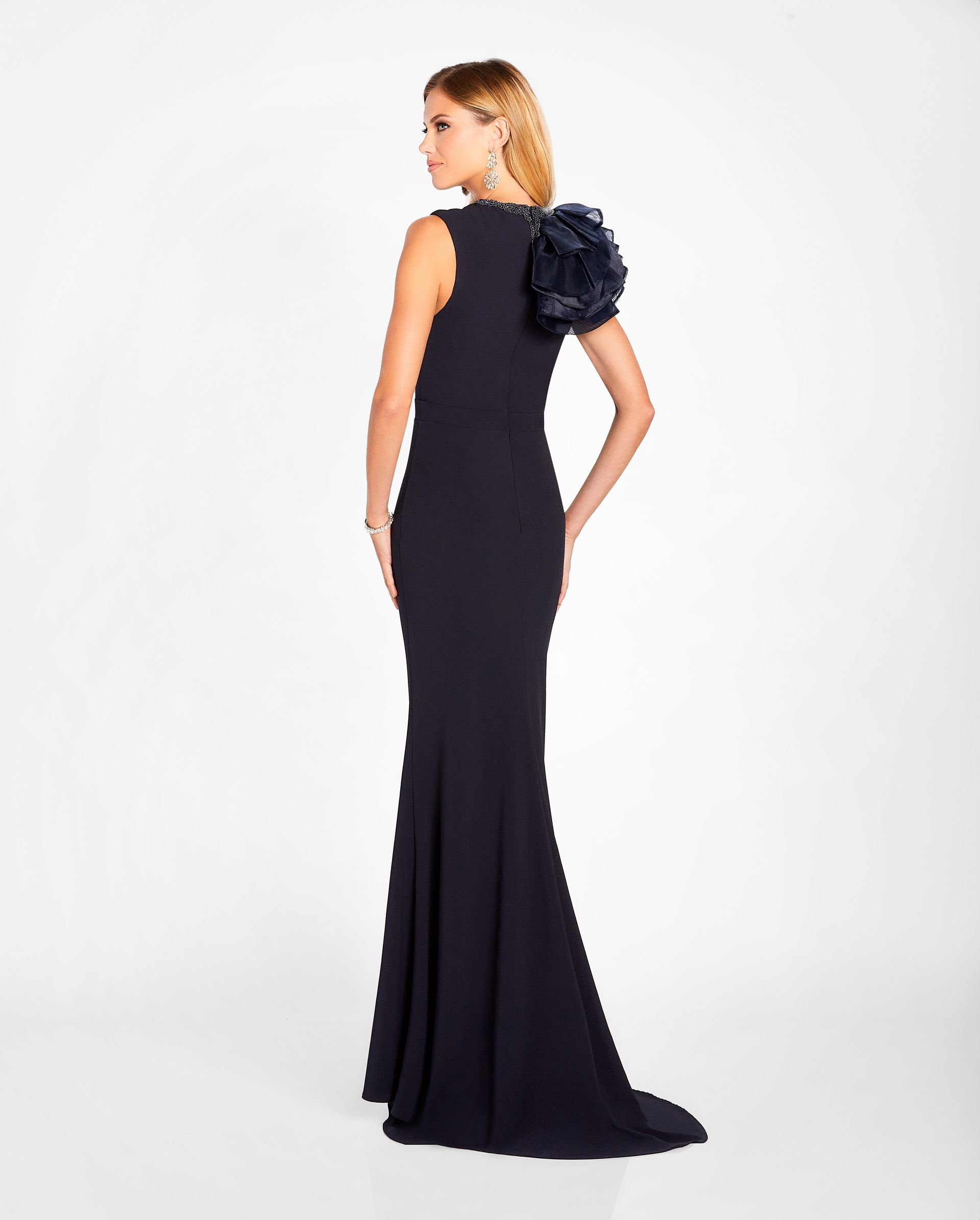 Woman in a navy formal gown with a large shoulder flower detail.