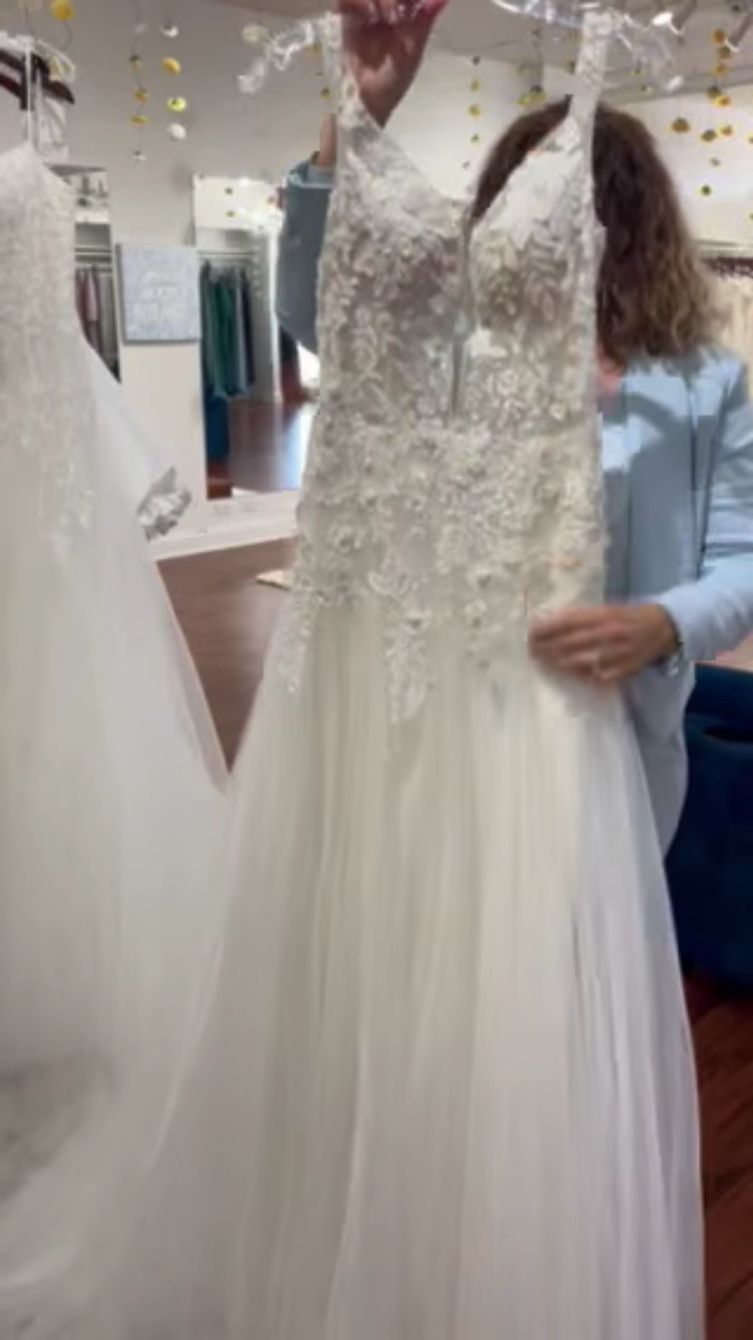 White wedding dress on display in a bridal shop, with a full tulle skirt and long train