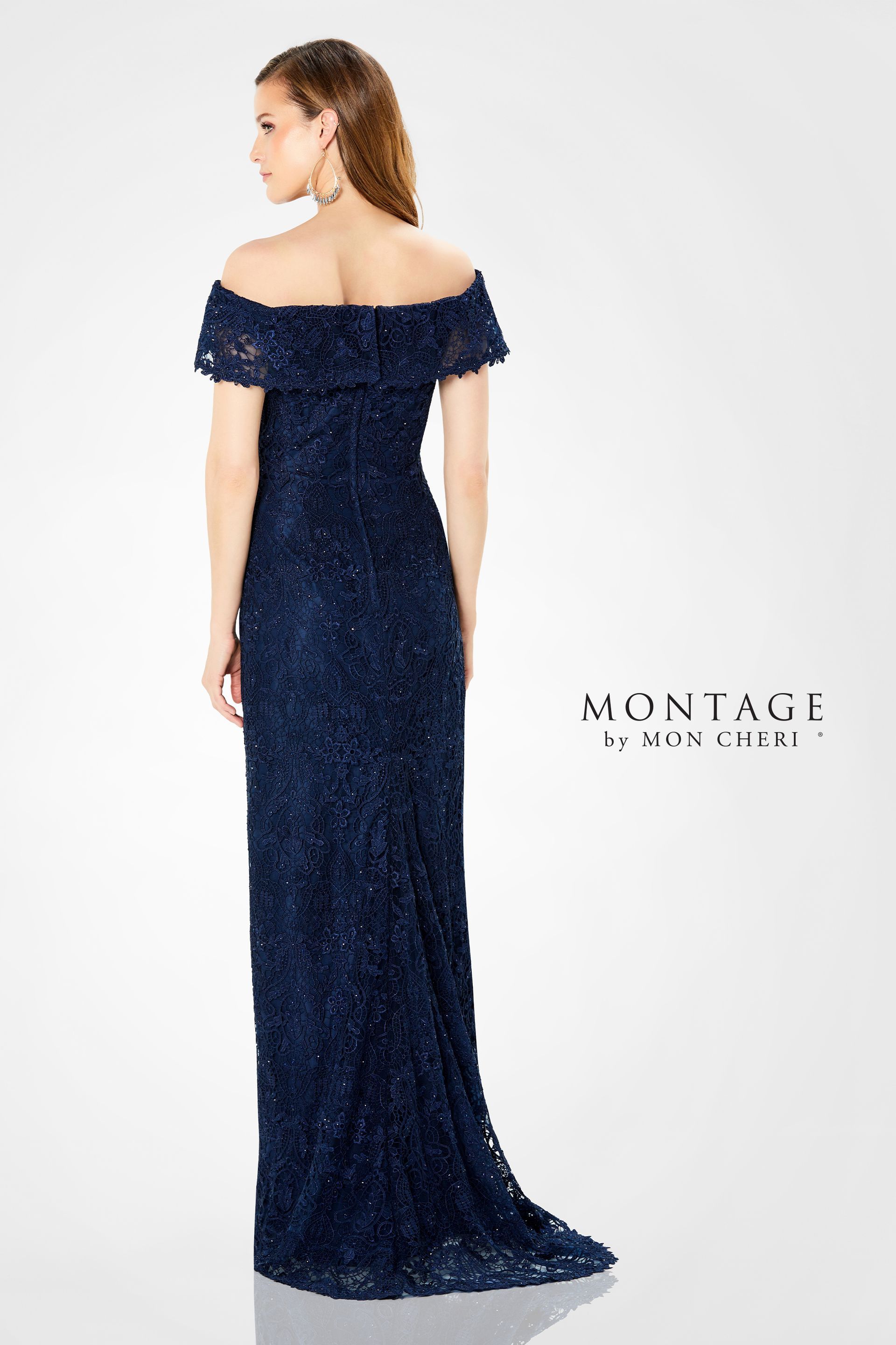 Woman in a gray, beaded, off-the-shoulder formal gown, posing indoors.