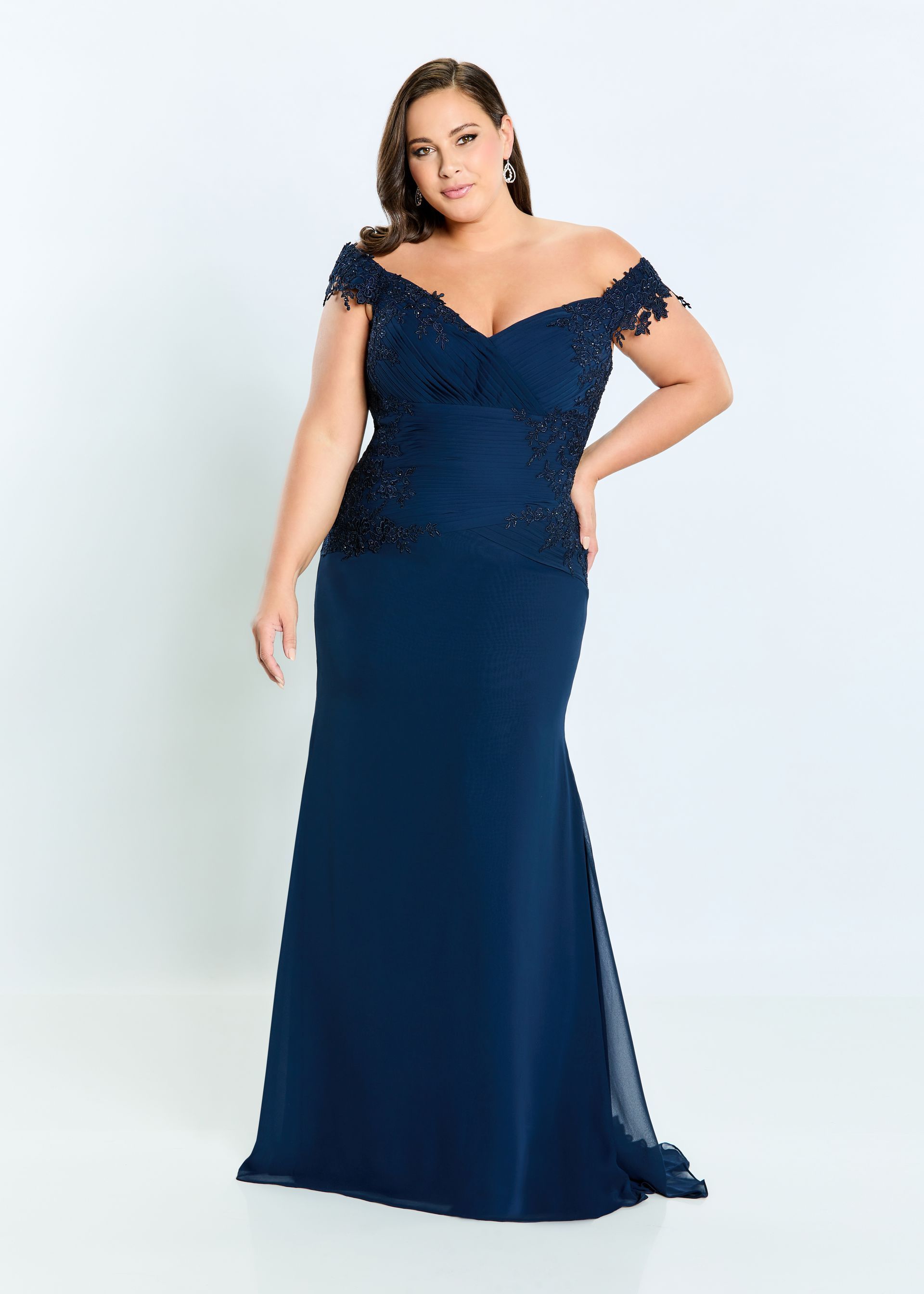 Woman in navy off-the-shoulder gown, posing in a studio.