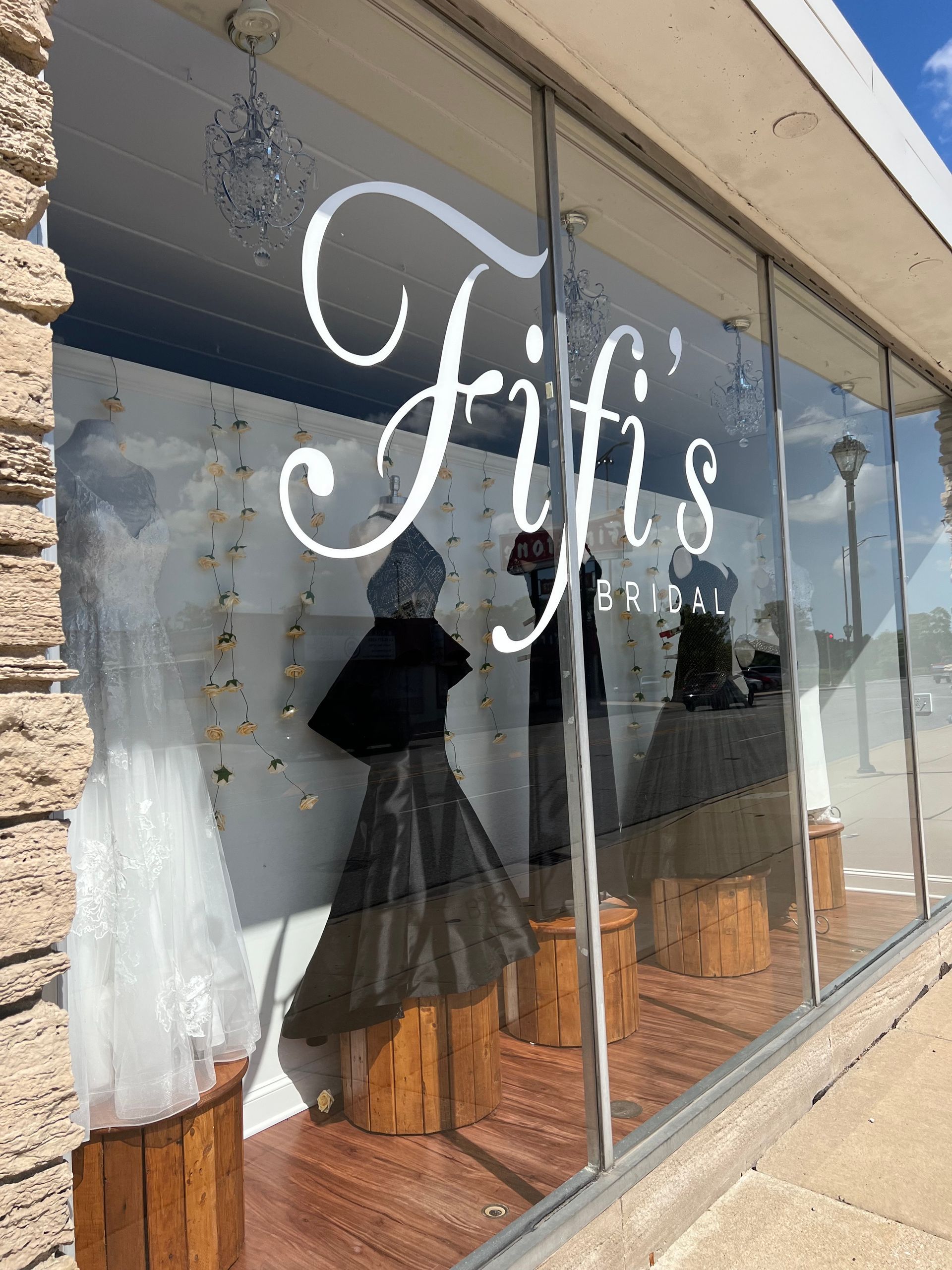 Fifi's bridal boutique storefront with dresses displayed in the window. White cursive logo on glass.
