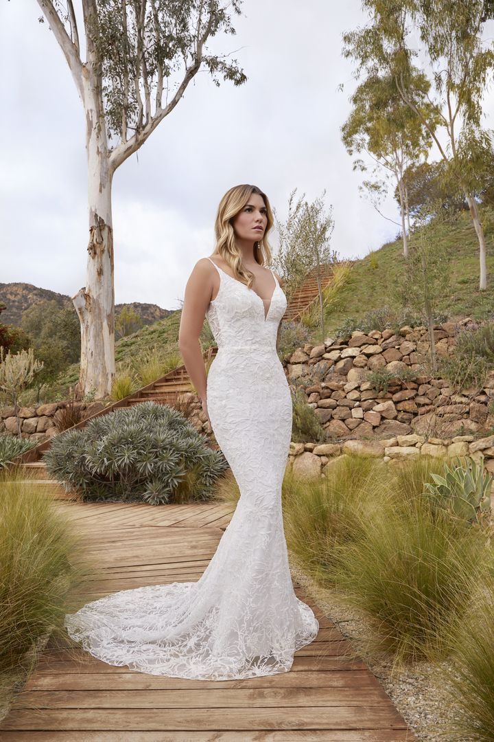 Woman in a beaded white wedding dress on a path with a long train.