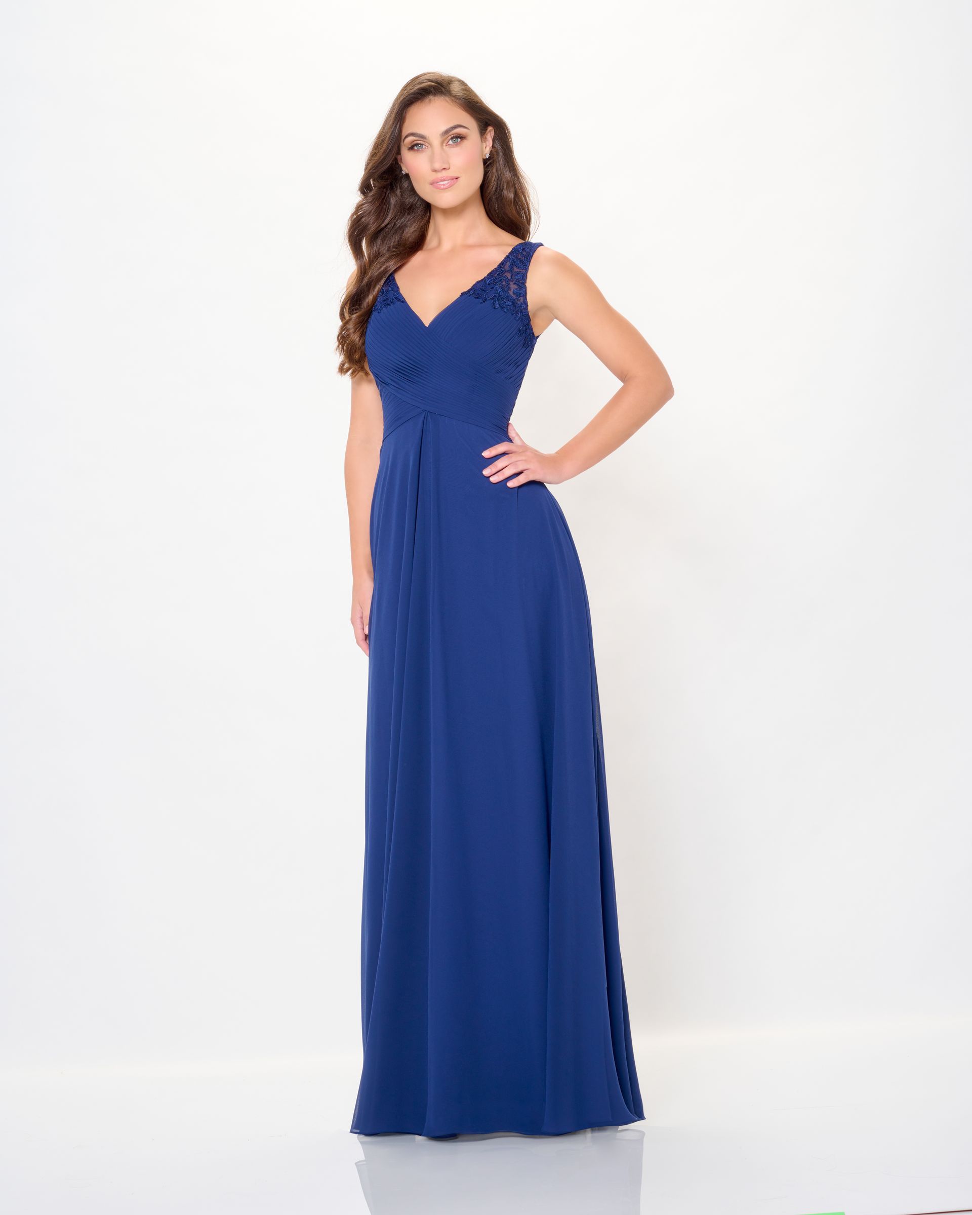 Woman in a blue formal gown with lace detail, posing against a white background.