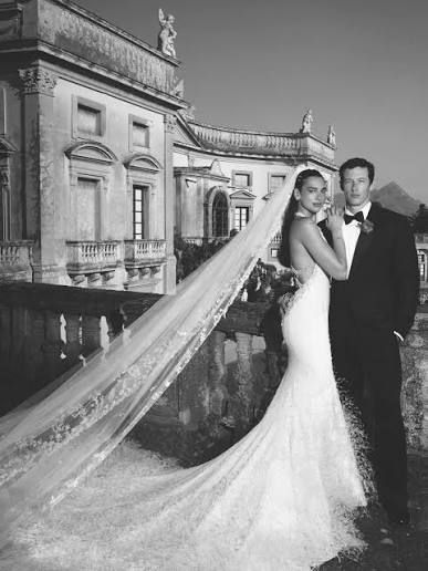 Bride and groom pose on a bridge, with the bride’s long veil flowing behind them. Bride and groom pose on a bridge, with the bride’s long veil flowing behind them.
