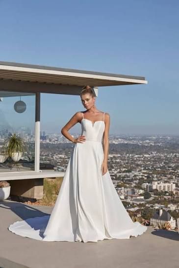 Bride in a white gown posing on a rooftop terrace with a city skyline in the background Bride in a white gown posing on a rooftop terrace with a city skyline in the background