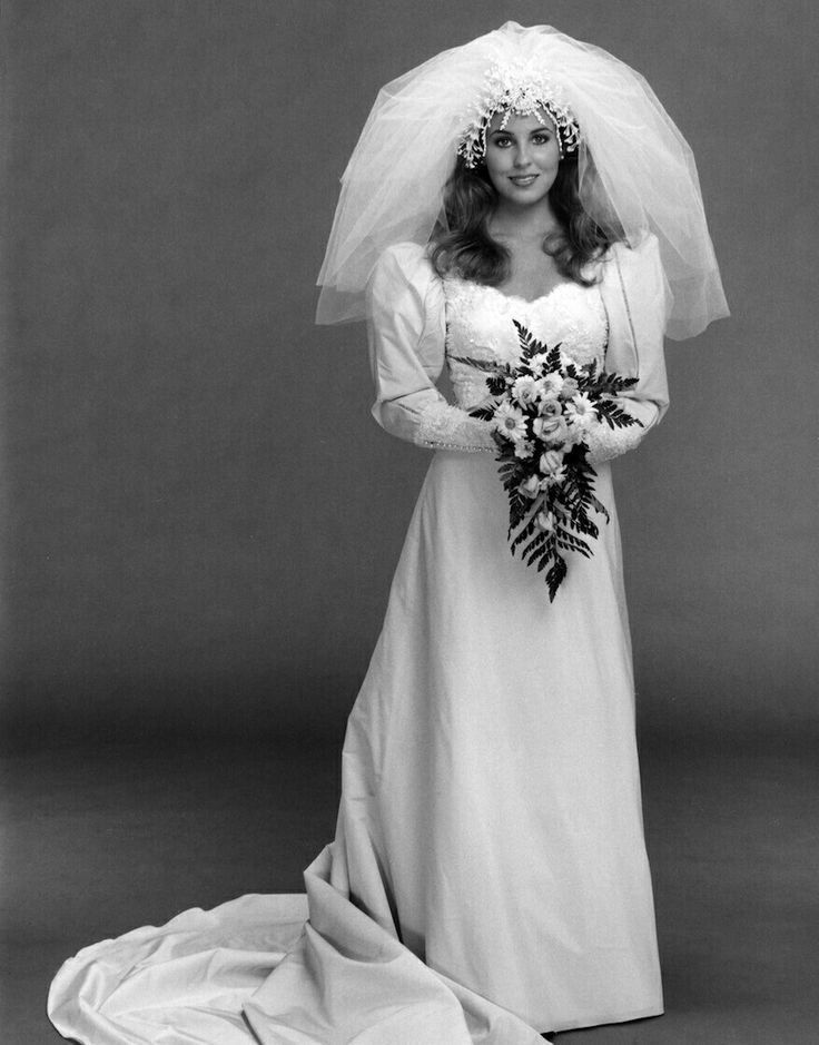 Bride in long white dress with veil and bouquet.
