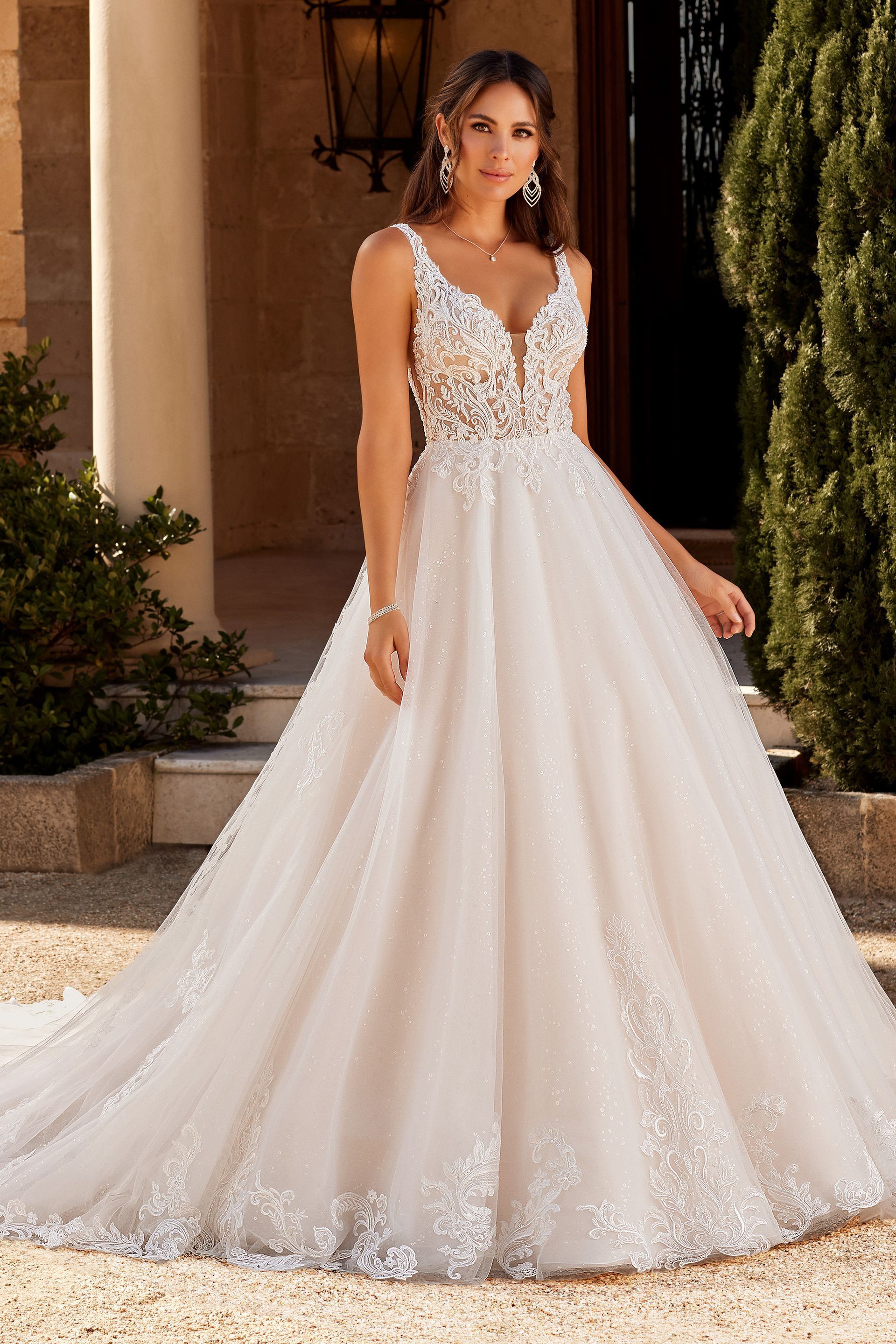 Woman in a white wedding gown with lace bodice and full skirt, standing outside.