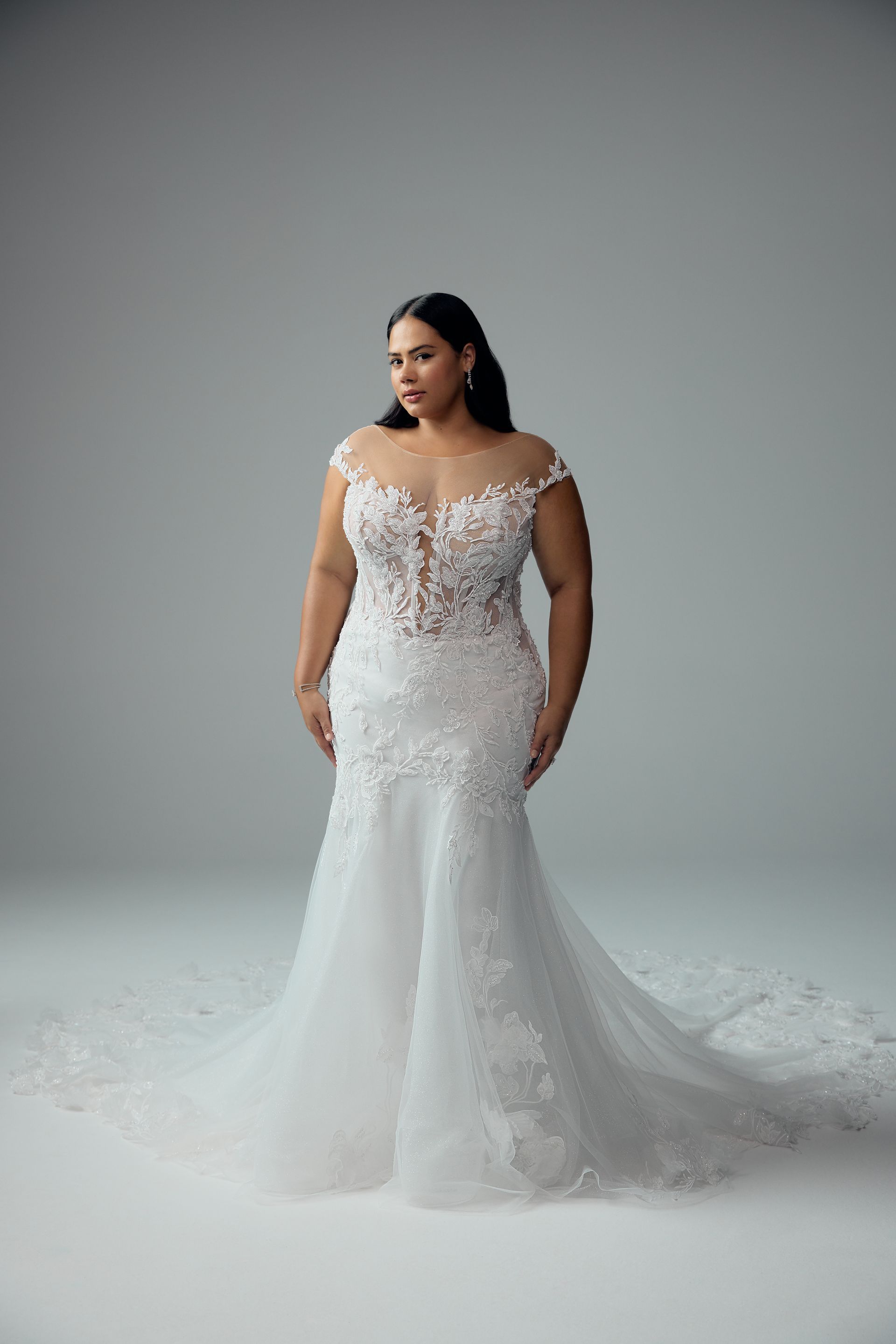 Woman in a white wedding gown, off-the-shoulder, floral detail on bodice and skirt, pose.