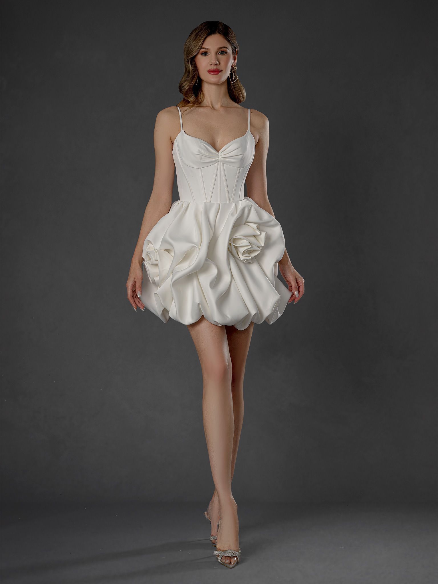Woman in short white dress with flower-like details, thin straps, and high heels.